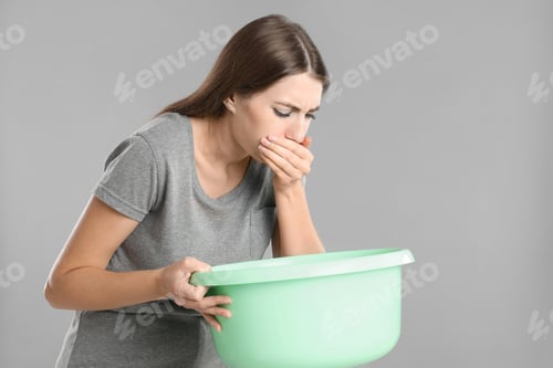 Preview: Woman with basin suffering from nausea on grey background. Food poisoning