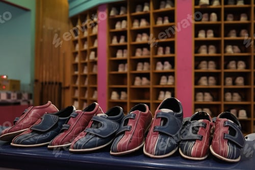 Preview: Bowling shoes lined up on counter with shoe rack in background