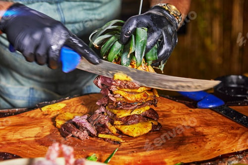 Preview: Chef Carving Grilled Meat with Pineapple