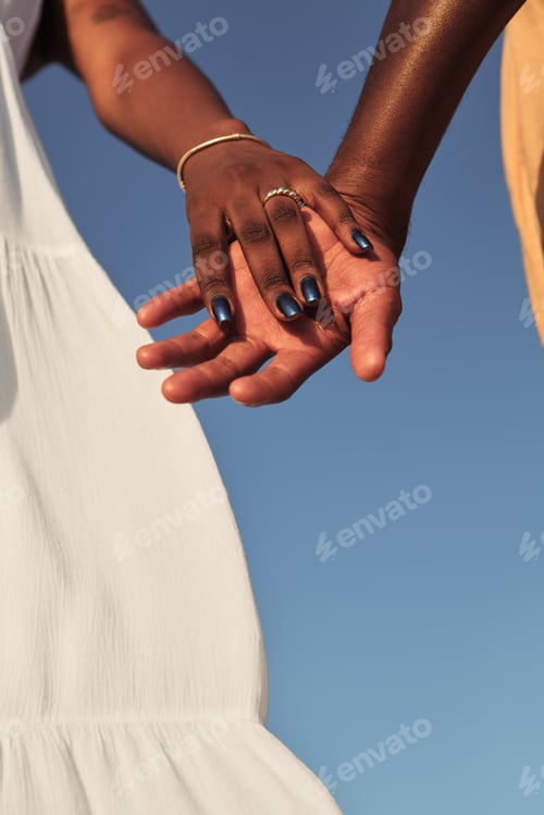 Preview: Crop African couple holding hands in sunlight