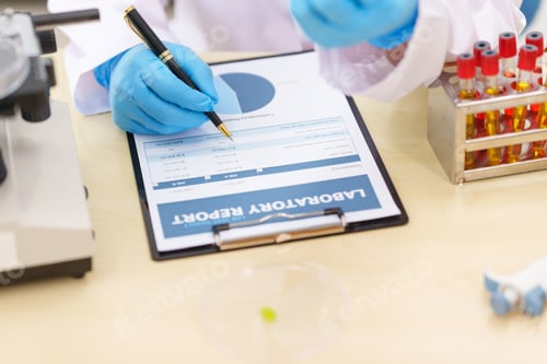 Preview: Two Asian scientists in lab coats sit at table in laboratory, examining samples through microscope