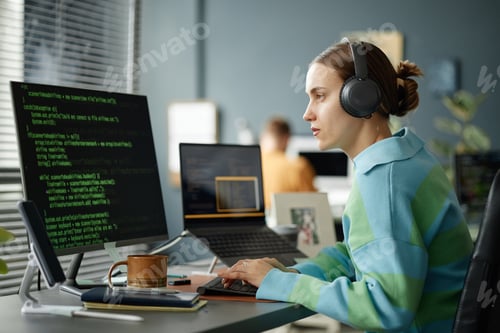 Preview: Young Woman Wearing Headphones Coding Software on Computer Monitor
