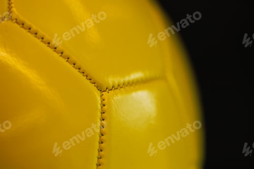 Preview: Close-up of the seams of a yellow sports ball on a dark background