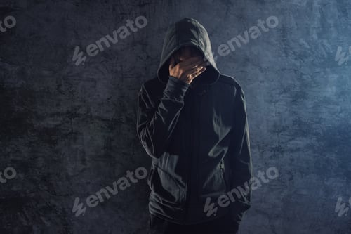 Preview: Depressed hooded person leaning on wall and crying