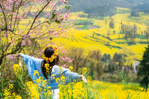 Preview: Young happy woman tourist enjoying the canola fields while traveling in Luoping, China