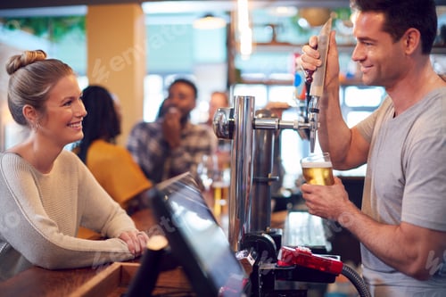 Vista previa: Smiling Male Bartender Behind Counter Serving Female Customer With Beer