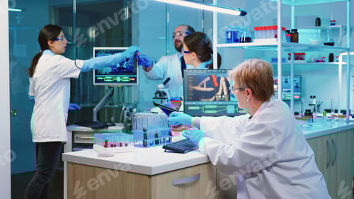 Preview: Nurse holding tablet computer and chemist using microscope