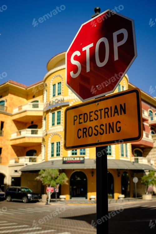 Preview: Urban street scene with a stop and pedestrian crossing sign in front of a colorful building