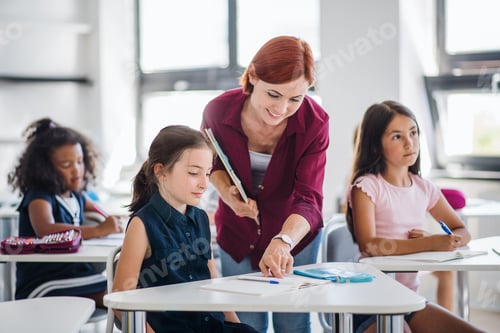 Preview: A teacher walking among small school children on the lesson, explaining