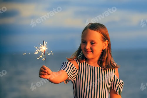 Preview: a schoolgirl girl meets a holiday with a Bengal fire in her hand on the ocean