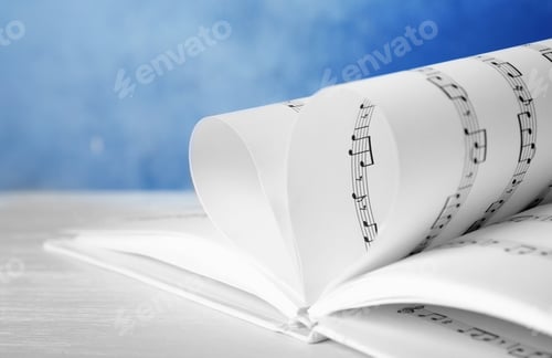 Preview: Heart made of book pages with music notes on table against color background, closeup. Space for text