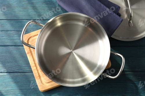 Preview: Empty metal pot on cutting board on wooden table