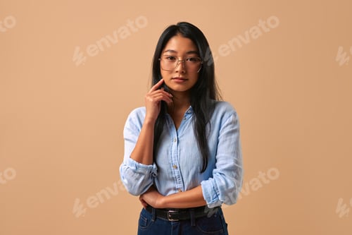 Preview: A Confident Young Woman Posing in a Casual Outfit with Style Against a Beige Background