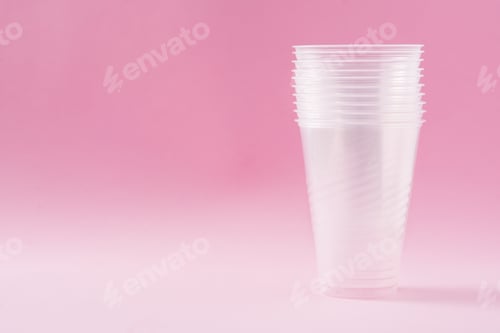 Preview: Disposable waste plastic glass on pink background.