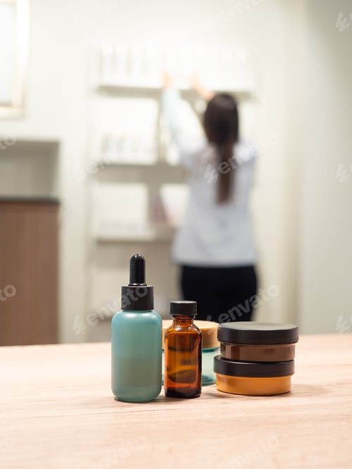 Preview: Skincare product bottles with blurred scientist working in lab