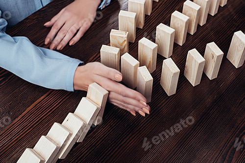 Preview: partial view of woman sitting at table and preventing wooden blocks from falling