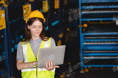 Preview: A woman wearing a yellow vest and a hard hat is looking at a laptop computer