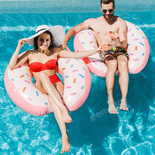 Preview: overhead view of young woman in straw hat and handsome man holding cocktail glasses