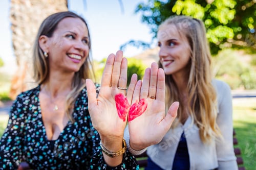 Preview: Mother and daughter with a heart drawn on their hand are smiling and looking at each other