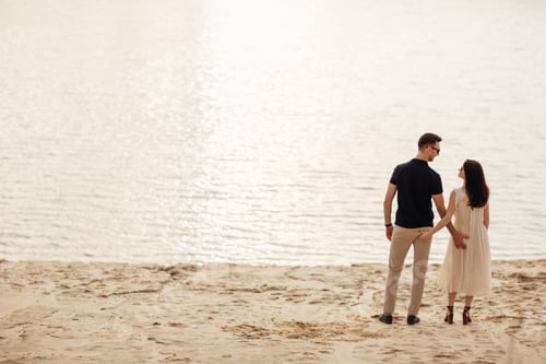 Vista previa: Pareja joven de pie cerca del lago en la naturaleza. Un hombre y una mujer románticos se abrazan
al aire libre