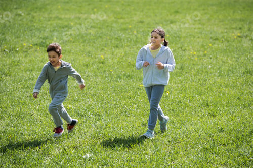 Preview: sister and brother running on meadow in park