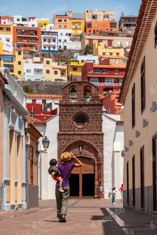 Preview: Vacation concept, mother with her son in her arms in the city of San Sebastian de la Gomera, Canary