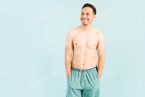 Preview: Relaxed young man in a swimsuit against a blue background