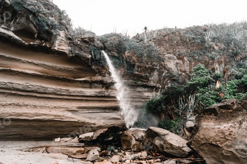 Preview: small waterfall with little water pushed by the force of the wind coming down from the large rocks