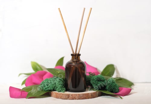Preview: home scent, reed diffuser on wooden podium with green leaves and petals decor.
