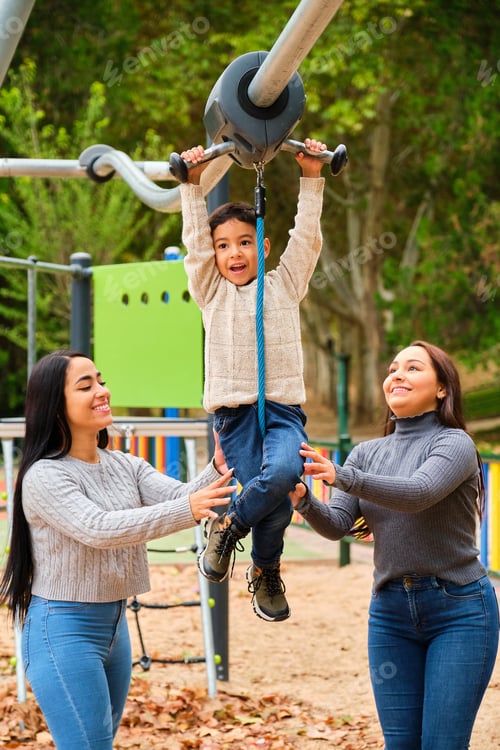 Preview: Lesbian couple playing with their son in the zip line at children's playground.