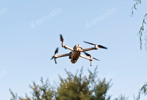 Preview: Low angle view of drone flying in air against blue sky.