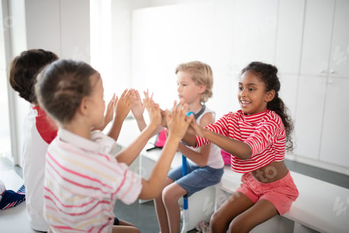 Preview: Boys and girls clapping their hands while sitting in locker room