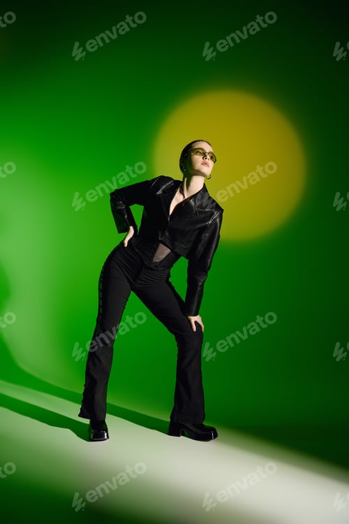Preview: Striking pose of a stylish young woman in black attire against a vibrant green backdrop