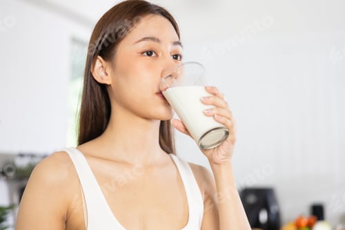Preview: Young Asian Thai woman holding glass of milk and drinking
