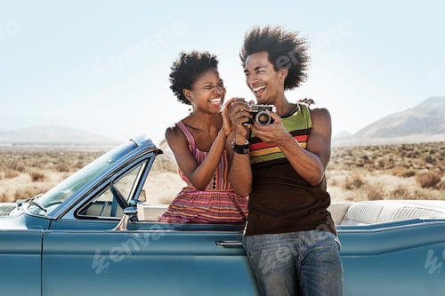 Preview: A young couple, man and woman in a pale blue convertible on the open road