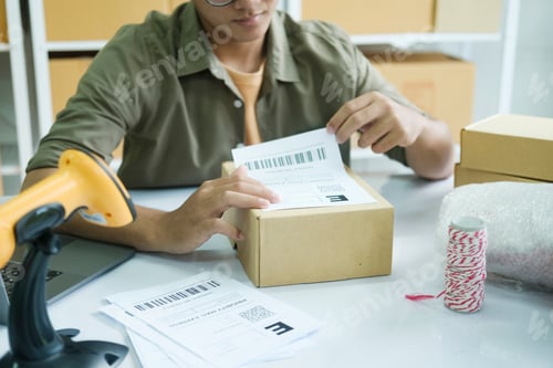 Preview: Young entrepreneur packing online order product for shipping.