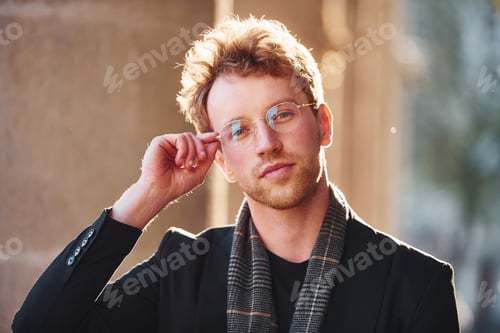Preview: Portrait of elegant young man in glasses and formal classy clothes outdoors in the city