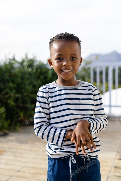 Preview: Portrait of happy african american boy staying on sunny terrace
