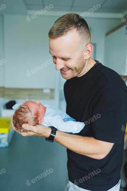 Preview: Happy young dad holding his newborn baby in his arms. Romper on a newborn boy.