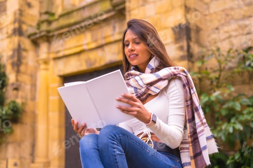 Preview: Latin woman with a white t-shirt, jeans and a scarf enjoying reading a book