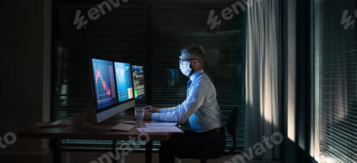 Preview: Businessman with computer sitting at desk, working late. Financial crisis concept