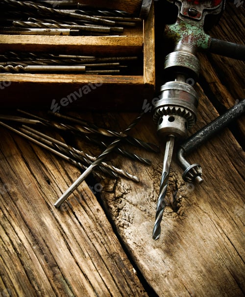 Preview: Old drill, box with drills on wooden background.