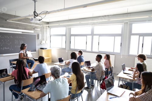 Visualização: Professora madura explicando a aula para estudantes multirraciais do ensino médio em sala de aula.