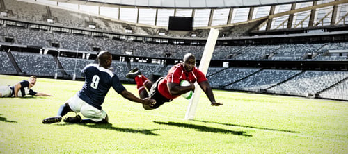 Preview: Digital composite image of rugby player jumping with the ball to score touchdown in sports stadium