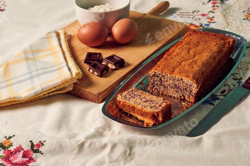 Preview: Homemade sponge cake on a white tablecloth with some ingredients: eggs, chocolate and flour