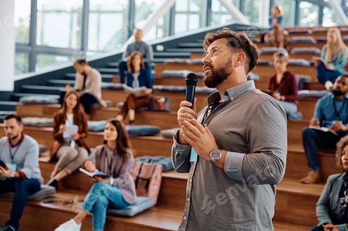Preview: Public speaker giving a presentation during business seminar in conference hall.