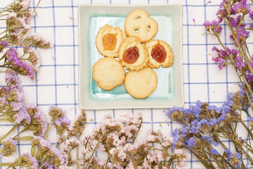 Preview: Flat lay of sweets, Danish butter cookie on plate with statice flower on blue gingham cloth
