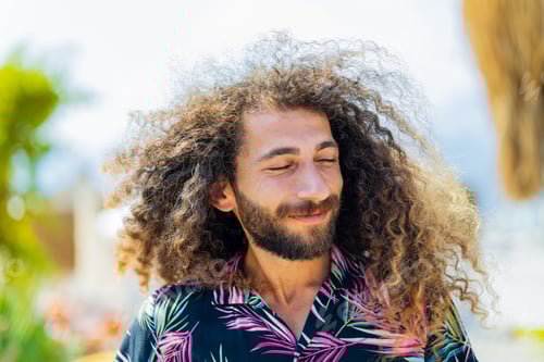 Preview: mixed race man with curly long hair outdoors ar sunny day