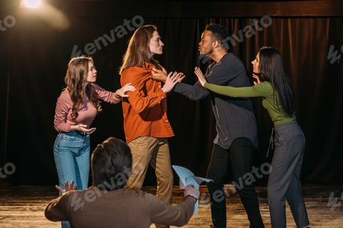Preview: multicultural actors and actresses rehearsing fight on stage in theatre