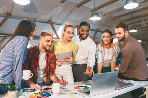 Preview: Group of People Standing Around Table With Laptop